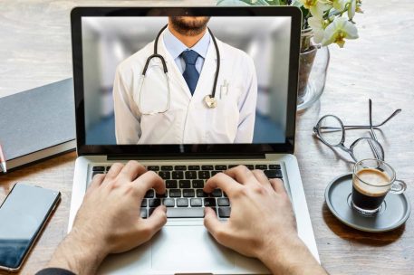 Telemedicine concept. Doctor GP on a computer screen, office desk background